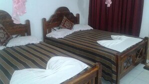A room with two wooden beds, each with a striped bedspread and white pillows. - Dilshan Guest House (Polonnaruwa)