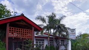 A building with a red roof and a sign advertising guest rooms. - Dilshan Guest House (Polonnaruwa)