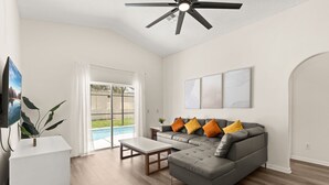A modern living room with a sectional sofa, a coffee table, and a ceiling fan.