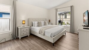 A bedroom with a bed, bedside tables, a TV, and a window with curtains.