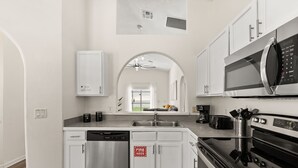 A modern kitchen with white cabinetry, stainless steel appliances, and a dishwasher.