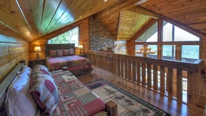 Een gezellig chalet met een slaapkamer op de entresol, houten vloeren, een stenen open haard en een balkon met een leuning.