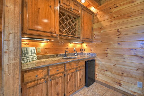 Una cocina tipo cabaña de madera con armarios empotrados, una estantería para vinos y un lavavajillas integrado.