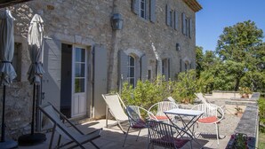 A stone building with a patio area featuring outdoor furniture and umbrellas. - Stone Provencal farmhouse with panoramic view & swimming pool- Saint-Restitut (Saint-Restitut)
