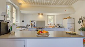 A spacious kitchen with a large island, white cabinetry, and a variety of kitchen appliances. - Stone Provencal farmhouse with panoramic view & swimming pool- Saint-Restitut (Saint-Restitut)