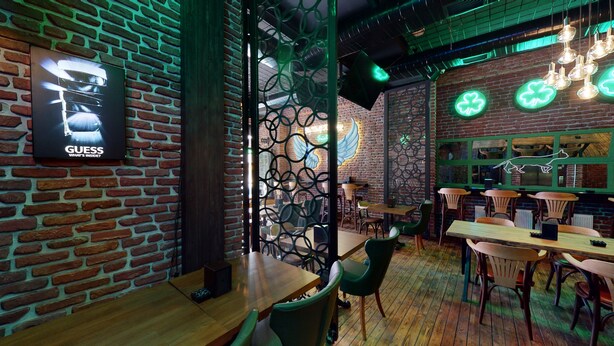 Un restaurante acogedor con paredes de ladrillo, mesas de madera y letreros de neón verdes.