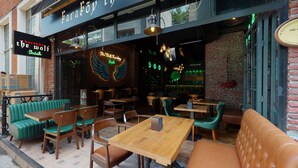 Un restaurante acogedor con una pared de ladrillo rústica, mesas y sillas de madera, y un letrero de neón que dice "The Wolf Irish".