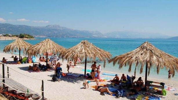 A beach with thatched umbrellas, sun loungers, and people relaxing. - Villa Lodi - new modern villa  few steps from beach with heated pool (Kaštel Štafilić)