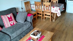 Ein gemütliches Wohnzimmer mit grauem Sofa, einem Holzespeisetisch, Stühlen, einer Treppe und einer kleinen Küchenzeile.