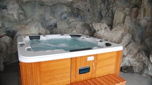Una bañera de madera con asiento incorporado, con un muro de roca de fondo.