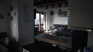 Una cocina moderna con zona de comedor, que incluye una mesa de madera, un sofá y luces colgantes.