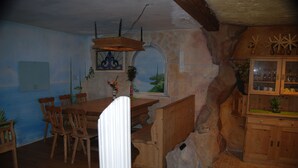 Un comedor rústico con mesa y sillas de madera, paredes de piedra y chimenea de piedra.