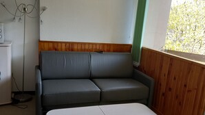 Een kamer met een grijze bank, een witte tafel en een ingelijst kunstwerk aan de muur.