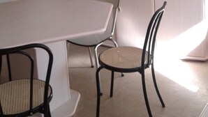 Een eetgedeelte met een tafel, stoelen, een plafondventilator, een magnetron, een radio en een kast.
