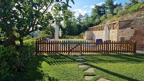 Un pati amb piscina, murs de pedra i tanca de fusta.