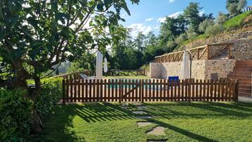Un giardino con piscina, muri in pietra e recinzione in legno.