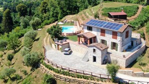 Una vila de pedra amb piscina, panells solars i una vista panoràmica a la vessant d'una collada.
