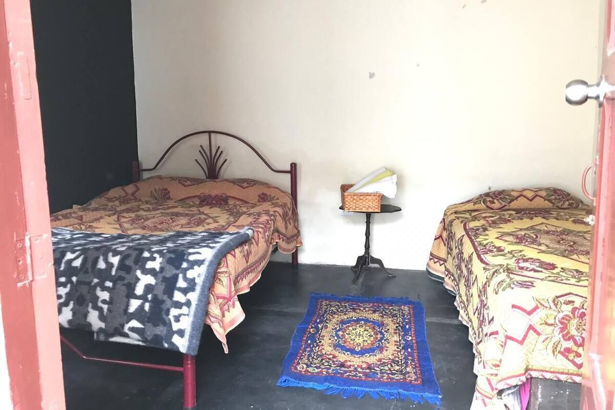 A room with two beds, a small table, and a patterned rug.