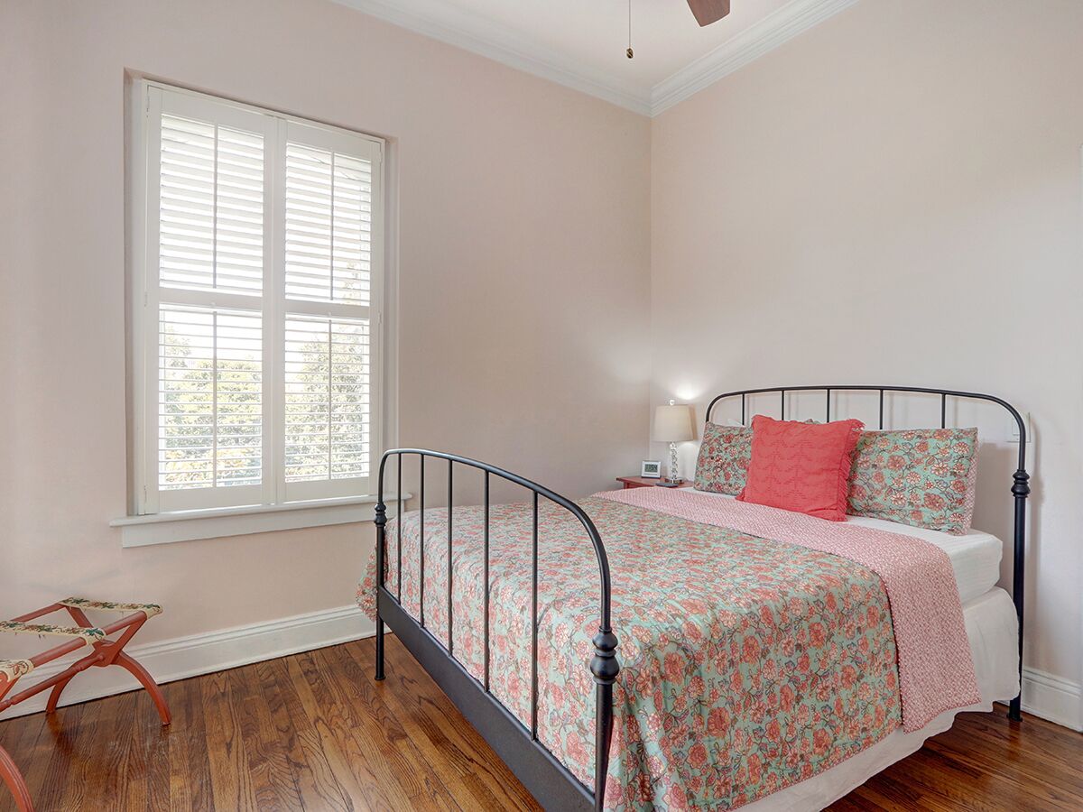 Un dormitorio con una cama, una ventana, una silla y una mesita de noche.
