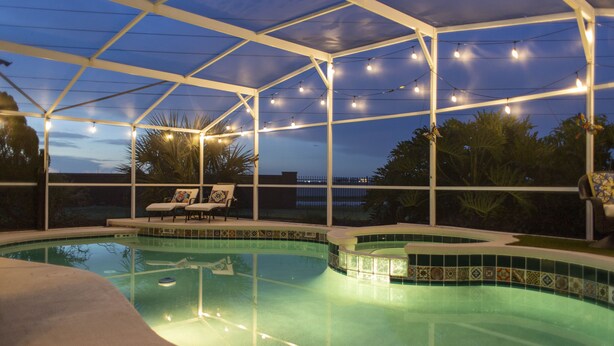 Ein Swimmingpool mit überdachtem Bereich, Liegestühlen und Lichterketten.