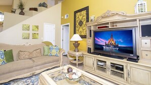 Ein Wohnzimmer mit einer Couch, einem Couchtisch, einem Fernseher und Dekorationselementen.