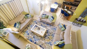 Ein geräumiges Wohnzimmer mit einem gemusterten Teppich, zwei Sofas mit Kissen, einem Couchtisch und einem Essbereich mit Stühlen und Tisch.