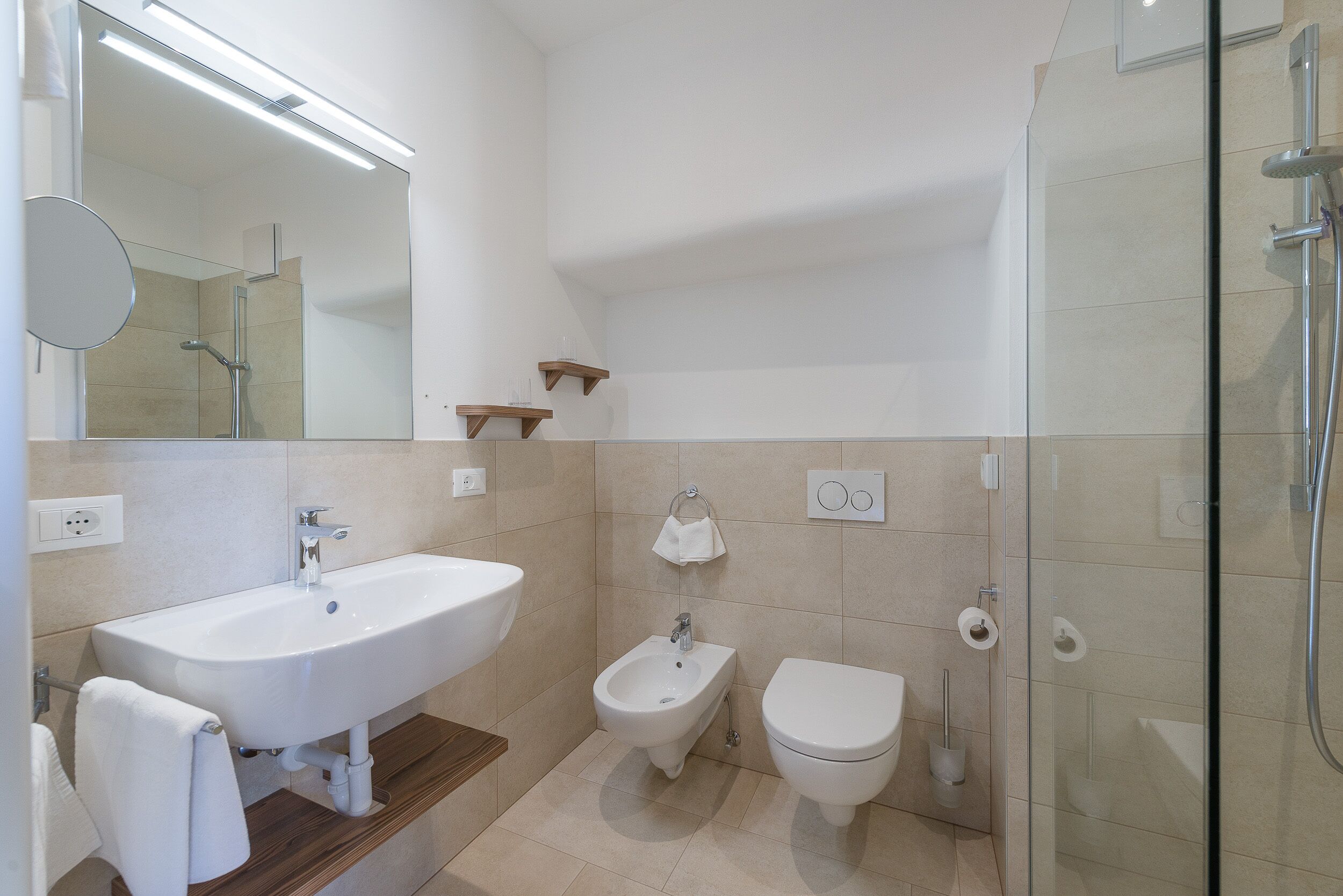 Un bagno moderno con un lavandino ampio, un bidet, il water e un box doccia in vetro.