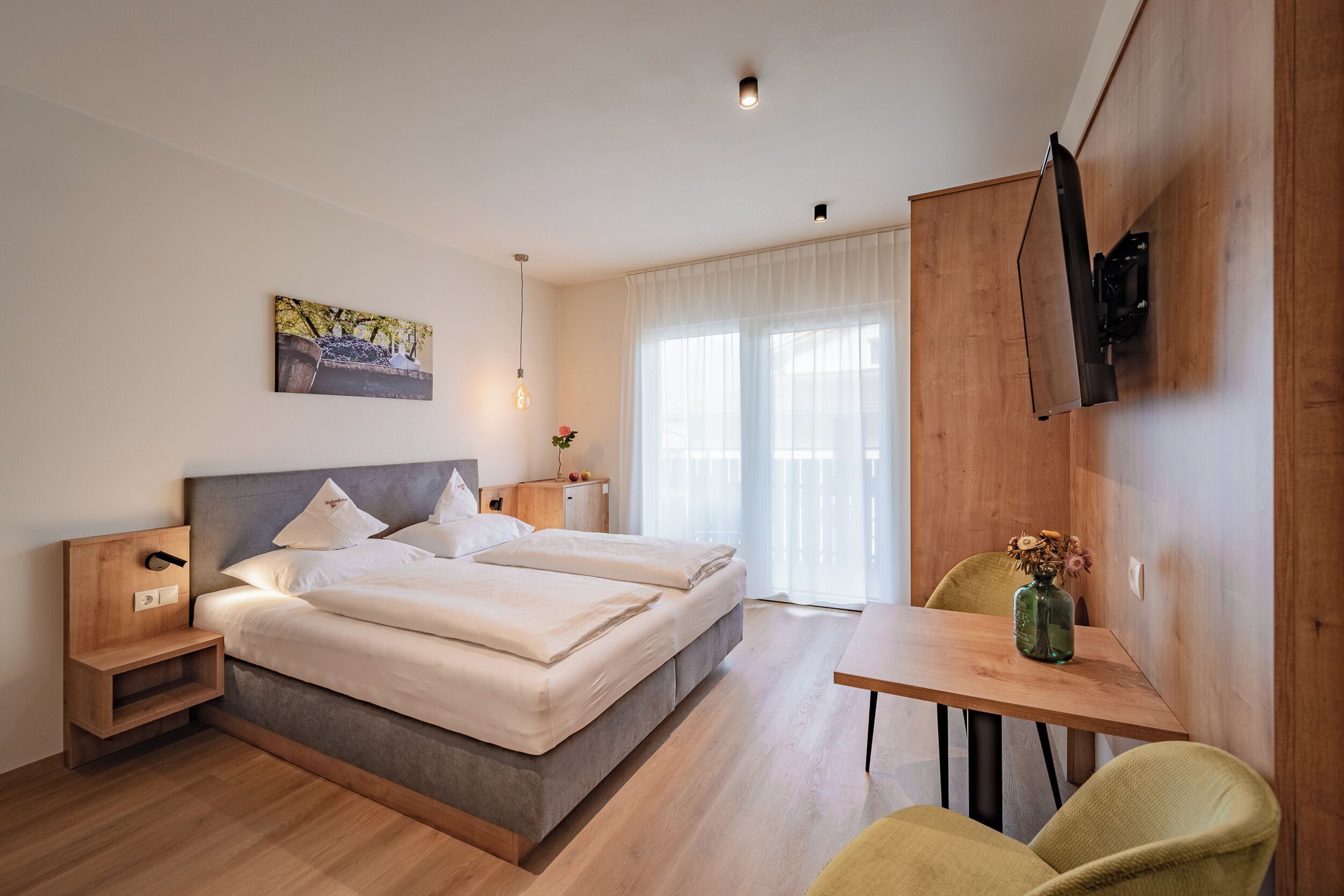 Une chambre d’hôtel moderne avec un grand lit, une petite table et un téléviseur fixé au mur.