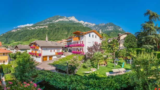 A mountain town with a church on a hill, houses with balconies, and a well-maintained garden. - Rebenheim Frühstückspension - FEWO (Termeno Sulla Strada del Vino)
