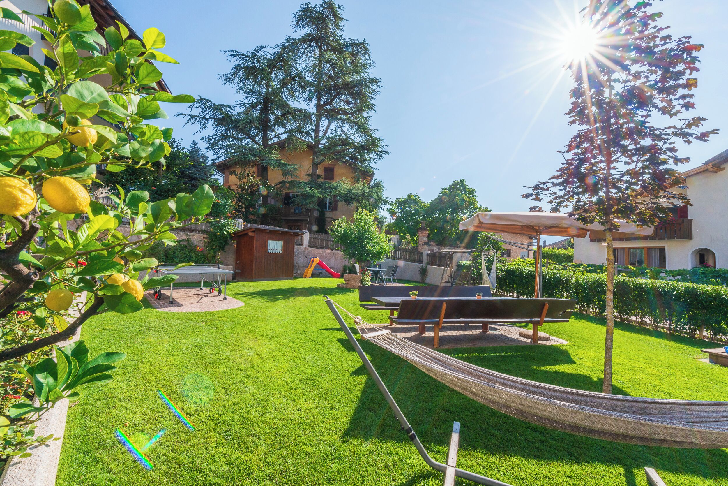 A well-maintained backyard with a hammock, a play area, and a patio with outdoor furniture.