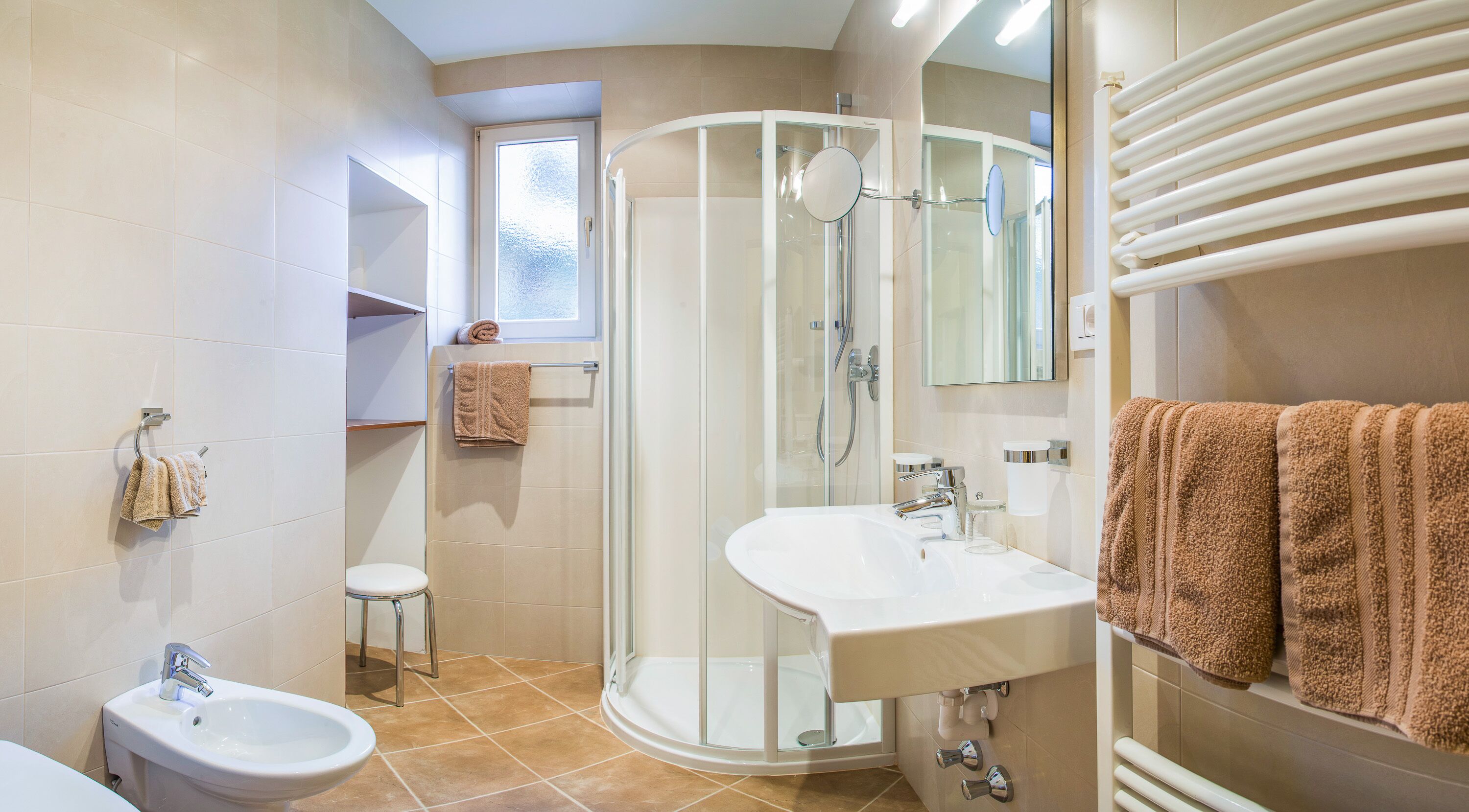 Une salle de bain moderne avec une douche à parois de verre, un lavabo, des toilettes et une fenêtre.