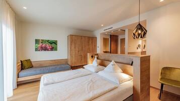 A modern bedroom with a large bed, a wooden headboard, a bench with cushions, and a hanging light fixture.