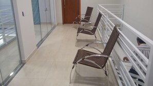 A corridor with a glass wall, a wooden door, and two metal chairs with metal frames. - Recanto do Tanaca Holiday homes (Olímpia)