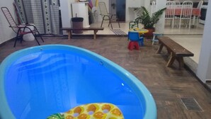 A swimming pool with a pineapple float, a wooden bench, and a dining area with chairs and a table. - Recanto do Tanaca Holiday homes (Olímpia)