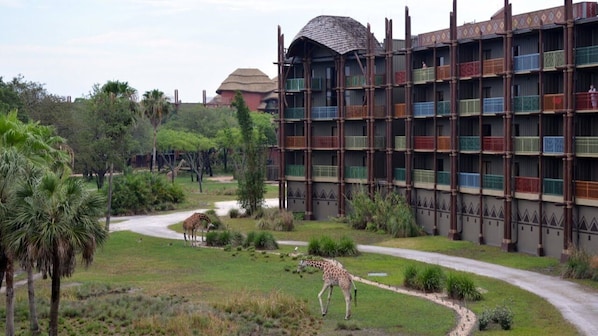 A building with multiple balconies, surrounded by a landscaped garden with a giraffe visible.