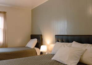 A hotel room with two beds, a nightstand, a lamp, and a window with curtains. - West Lodge – Spacious 3BR Mobridge Stay (Mobridge)