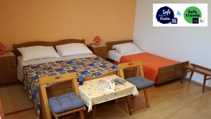 Une chambre avec deux lits, une table avec des chaises et un petit banc.