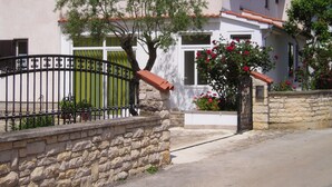 Un mur de pierre, un portail en métal et un bâtiment avec un toit en tuiles et des fenêtres.