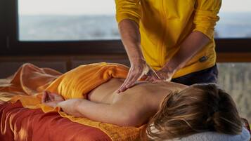 Relax in a serene space with a view, featuring a massage table and a comfortable bed.