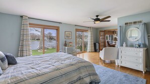 Une chambre avec un grand lit, une commode, un ventilateur de plafond et une vue sur l’extérieur.