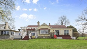 Une maison à deux étages avec un porche à l’avant, un hall d’entrée couvert et un petit jardin devant la maison.