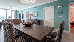 A dining area with a wooden table, wicker chairs, and a ceiling fan.