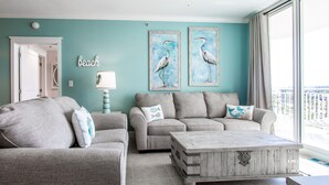 A living room with two grey sofas, a wooden coffee table, and teal walls.