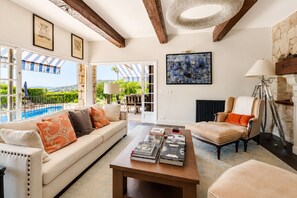 A spacious living room with a pool view, a large painting, and a cozy seating area.
