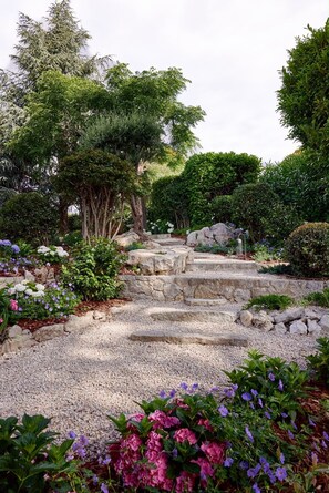 A garden with a gravel path, stone steps, and various plants.