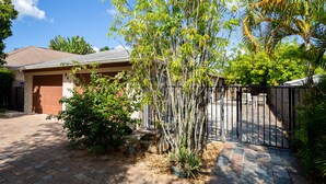 Un immobile residenziale con vialetto lastricato, garage e un cortile recintato con mobili da giardino.
