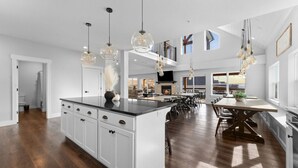 Una cocina amplia con una isla grande, iluminación colgante y vistas al salón.