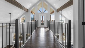 Un largo y estrecho pasillo con techo alto y vigas de madera, que conduce a una puerta al final.