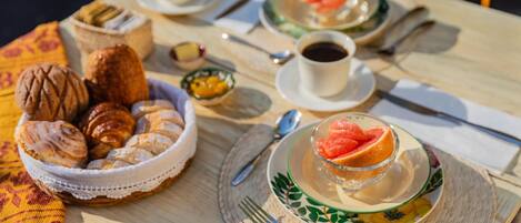 A table set with pastries, a bowl of nuts, a plate with a grapefruit, and two cups of coffee.