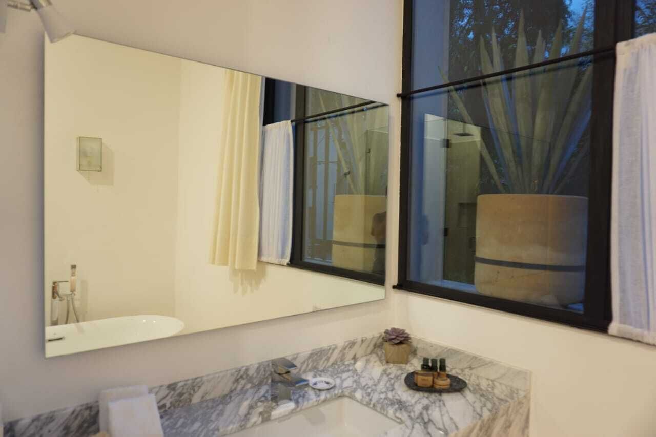 A bathroom with a large mirror, a bathtub, and a marble countertop.